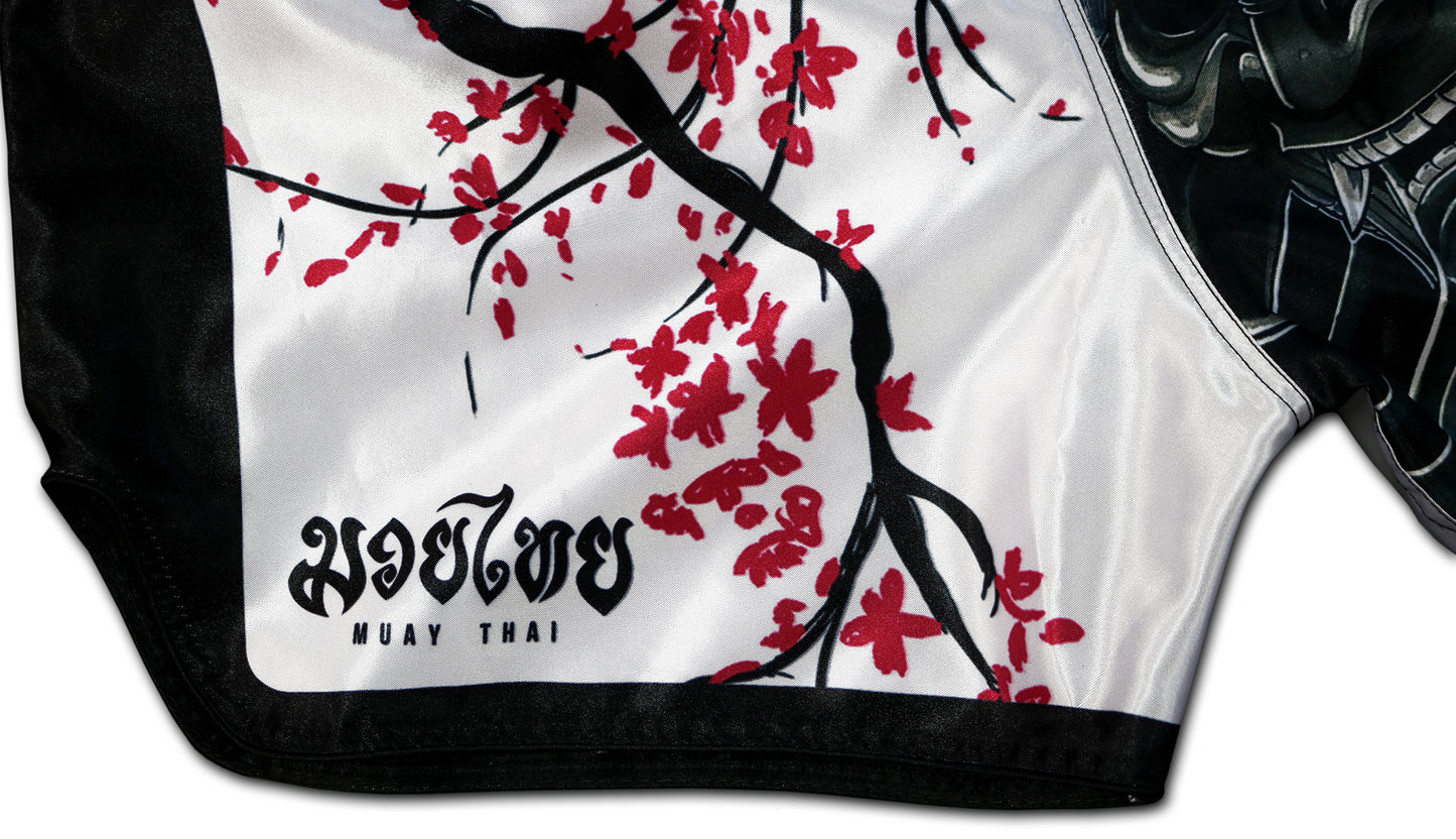 Close-up of the Sakura Muay Thai Shorts side detail, featuring sakura blossoms and traditional Muay Thai text, handcrafted in Thailand.