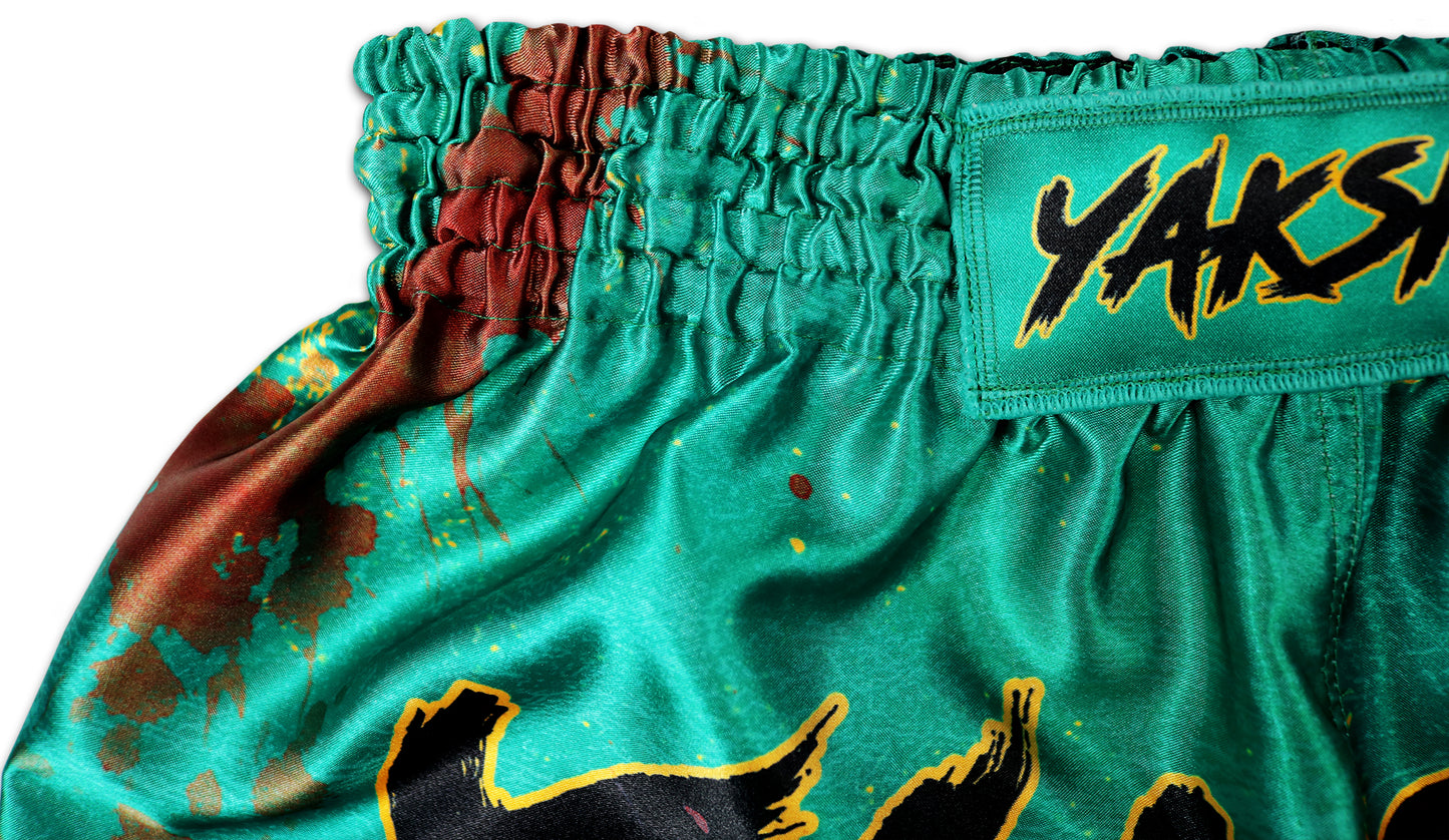 Detail picture of YAKSHA Muay Thai Shorts GRUNGE jade green with red blood splatter effect, showing elastic waistband stitching and YAKSHA logo patch.