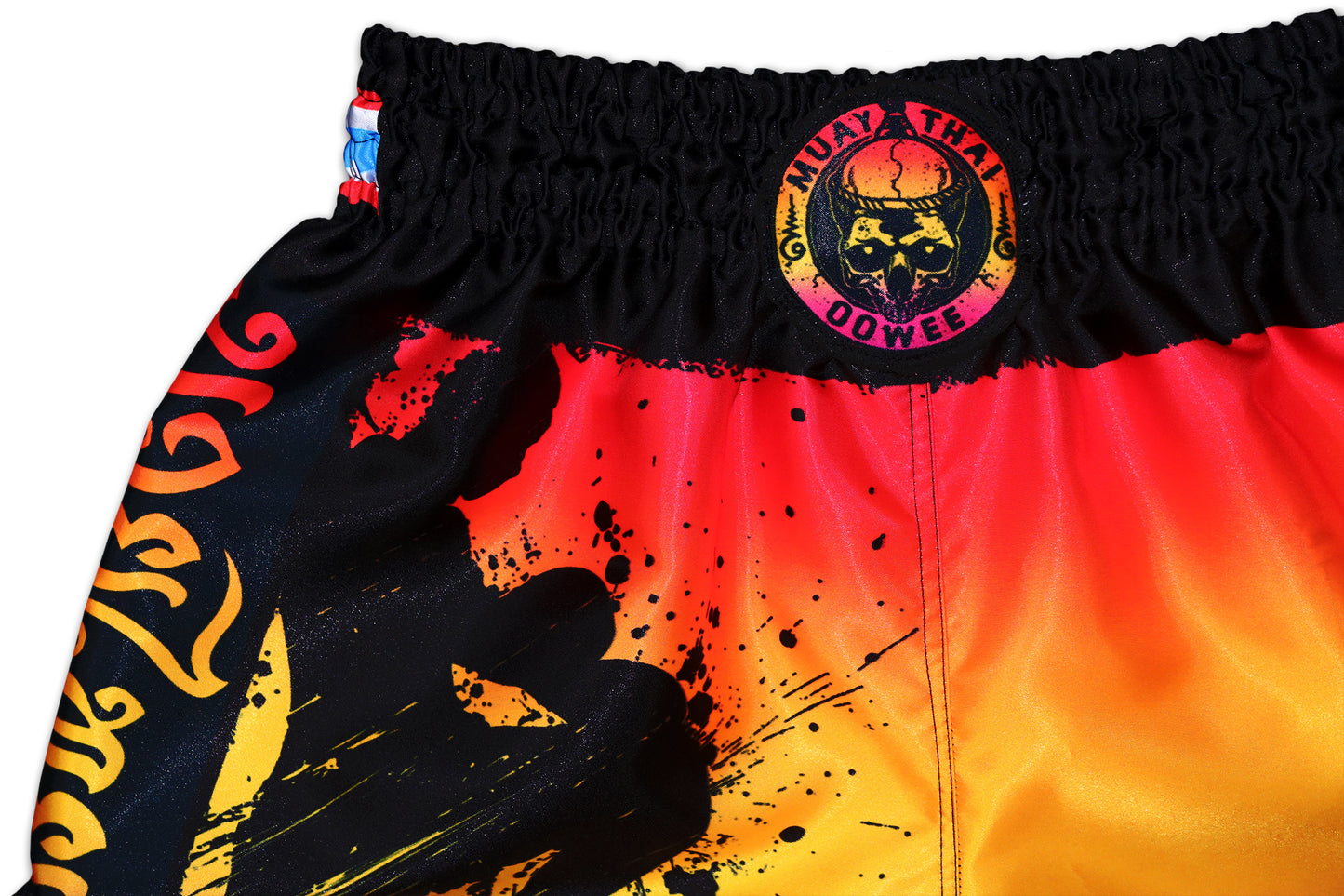 Detail picture of a Muay Thai Shorts from the brand OOWEE. The colors are like a sunset and on the front you can see a shillouette of a Muay Thai fighter