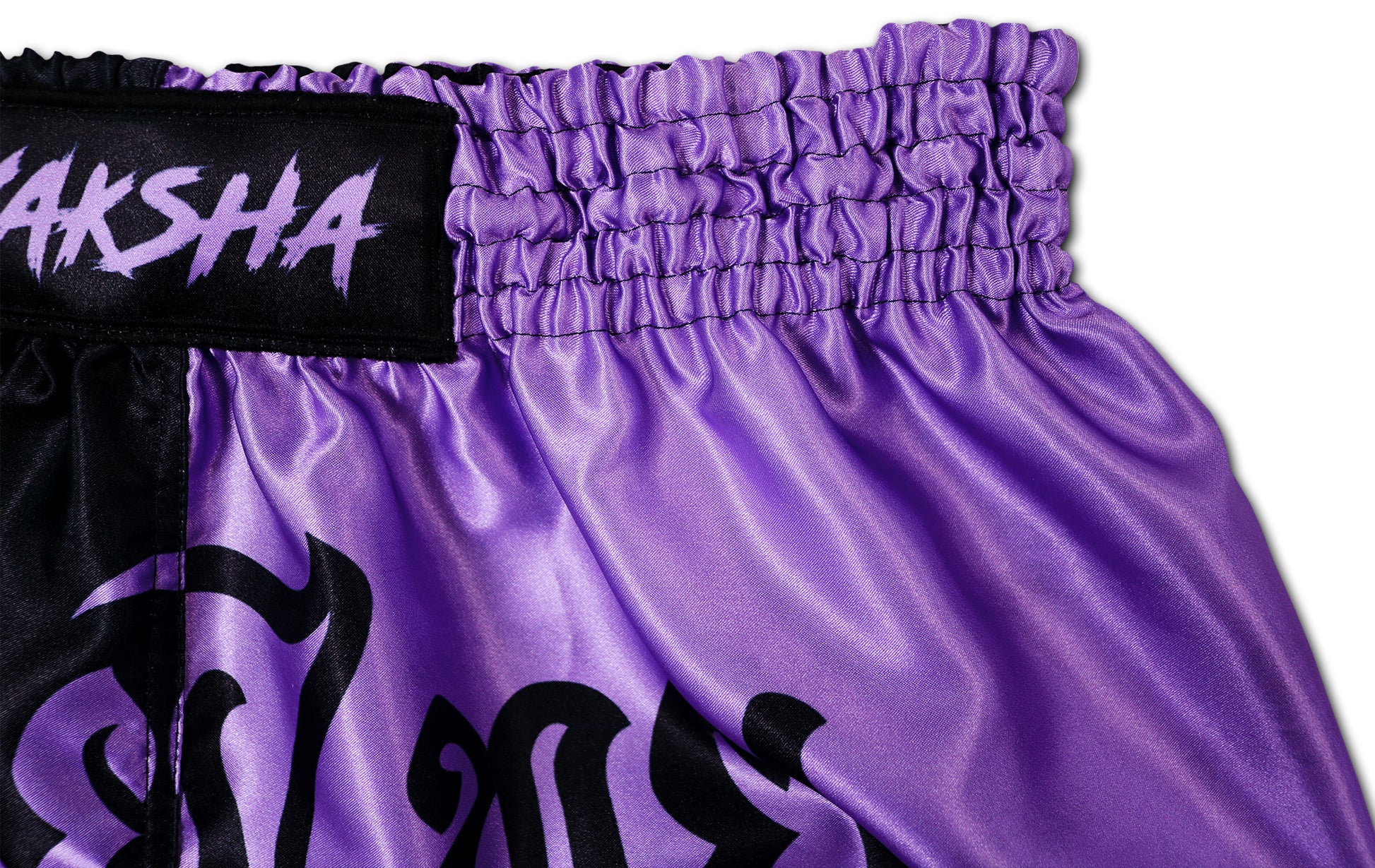 YAKSHA Luk Krung Muay Thai Shorts Black Lavender – close-up of elastic waistband with YAKSHA logo and premium lavender satin fabric