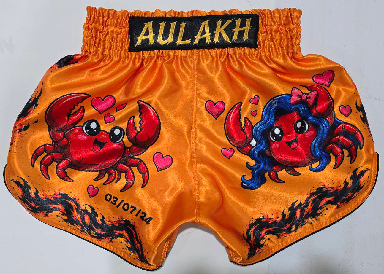 Orange Muay Thai shorts with cute crab couple design, hearts and flame print, custom name and date embroidered on waistband