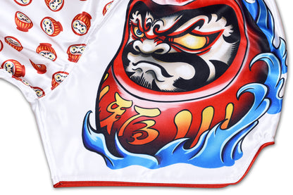 Detail of fierce daruma face graphic with blue waves, golden kanji and red trim on white Japan-inspired training shorts