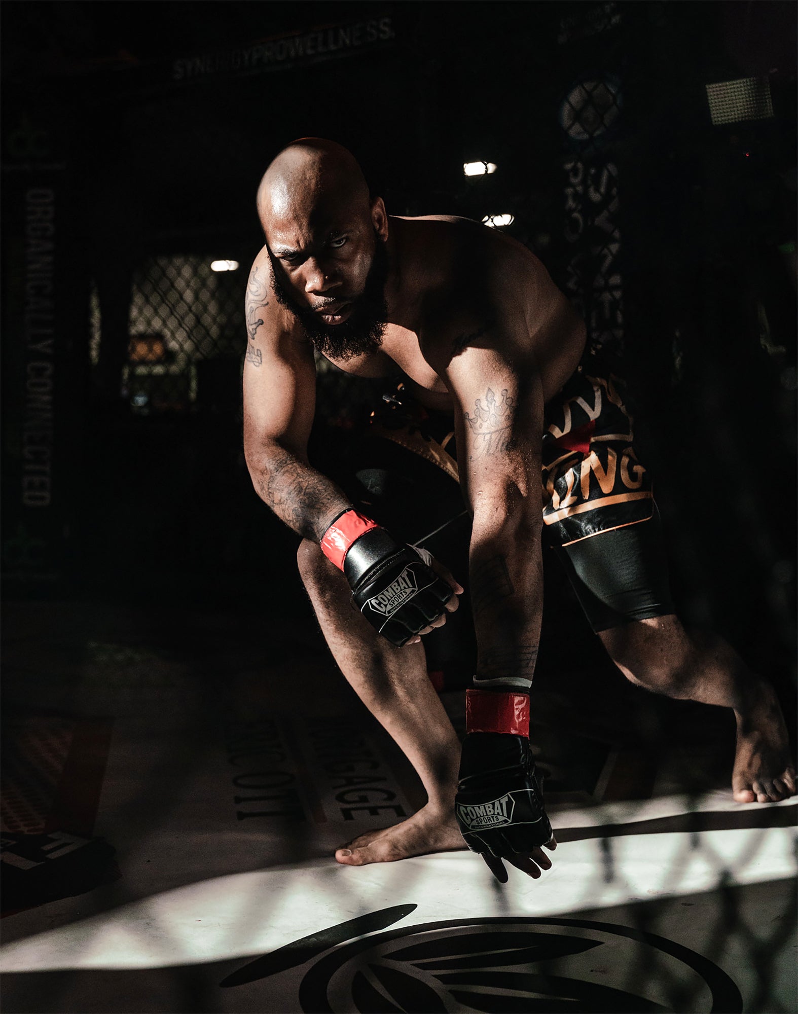 Fighter wearing KING Forever Muay Thai Boxing Shorts in black and gold during MMA training inside the cage