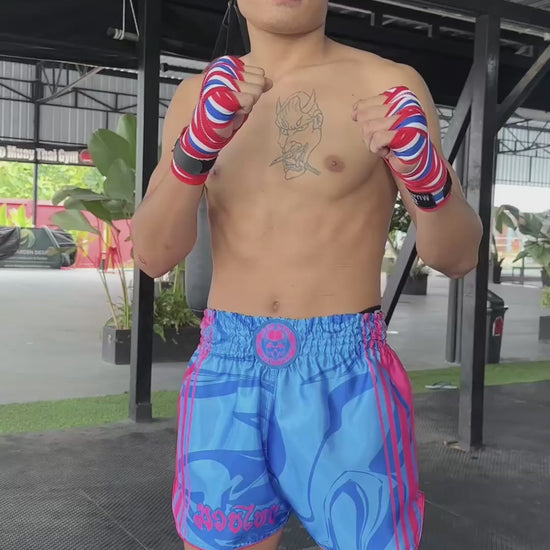 OOWEE Muay Thai shorts Art of 8 Limbs in action by male fighter showing kicks, teeps and punches on a heavy bag, size M