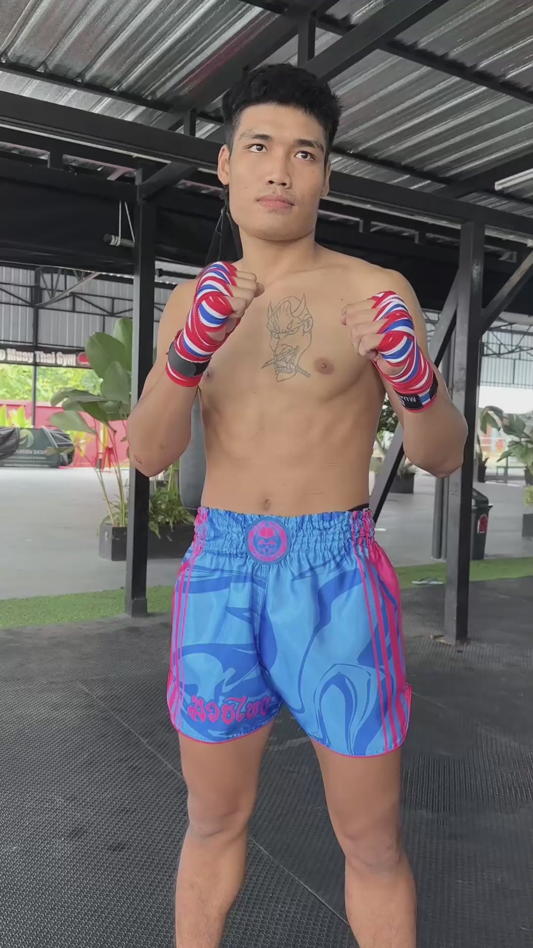 OOWEE Muay Thai shorts Art of 8 Limbs in action by male fighter showing kicks, teeps and punches on a heavy bag, size M