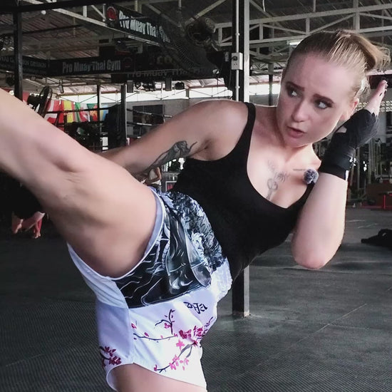 Muay Thai shorts in action by female fighter showing kicks, teeps and punches on a heavy bag
