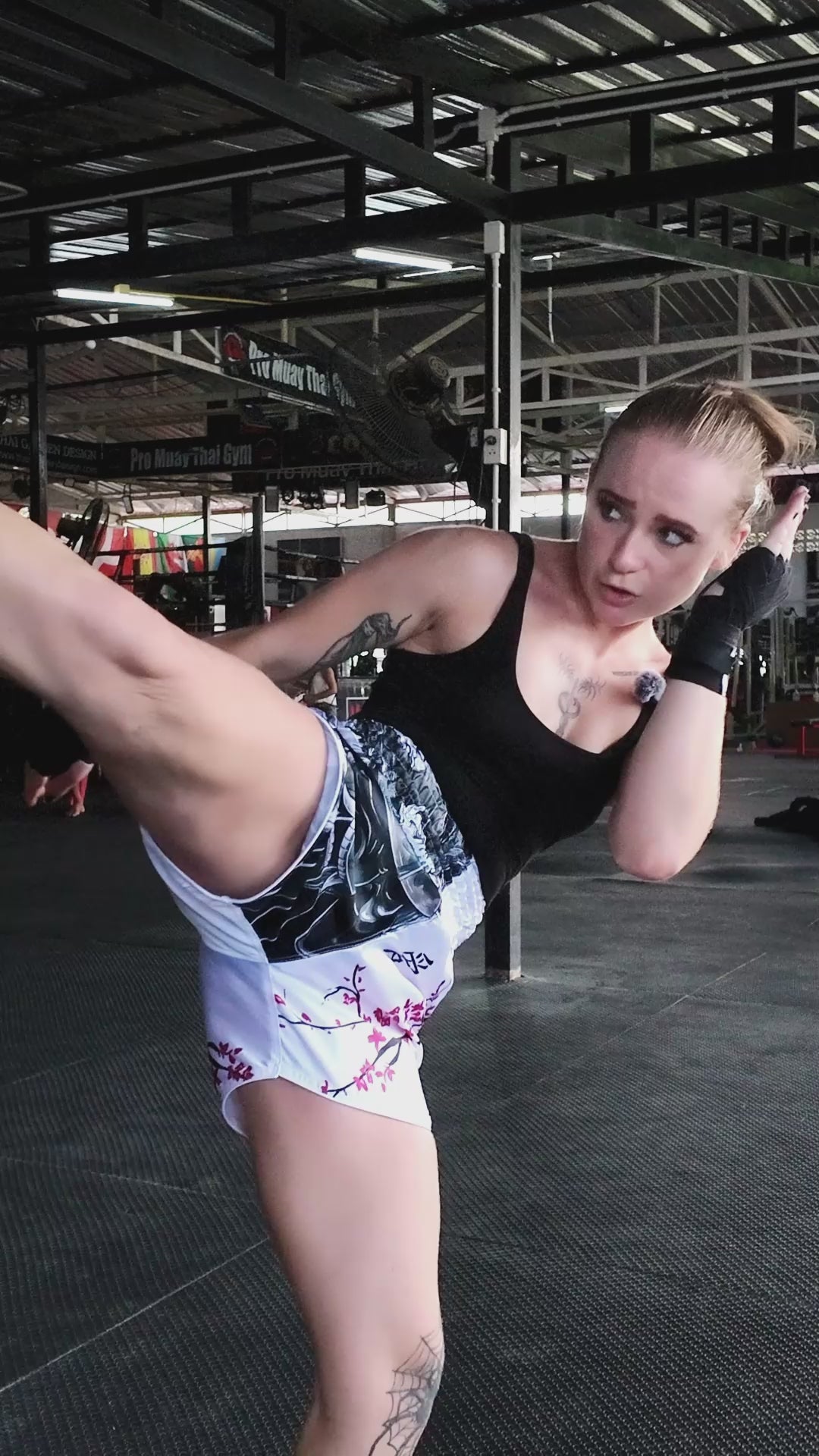Muay Thai shorts in action by female fighter showing kicks, teeps and punches on a heavy bag