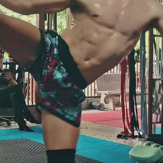 Muay Thai Fighter is wearing the Devils Koi Muay Thai shorts while shadow boxing, punching and kicking in the gym