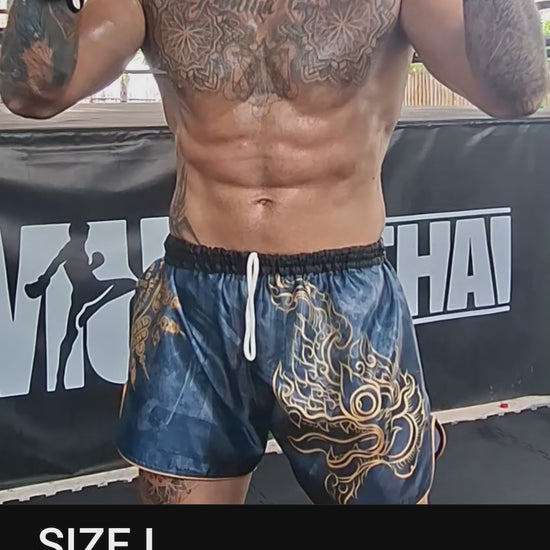 Muay Thai Fighter is wearing the black Phaya Naga Muay Thai shorts in size L while shadow boxing, punching and kicking in the gym