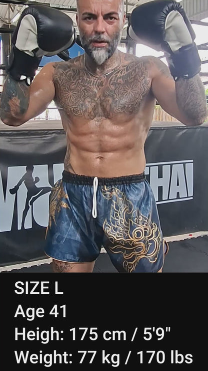 Muay Thai Fighter is wearing the black Phaya Naga Muay Thai shorts in size L while shadow boxing, punching and kicking in the gym