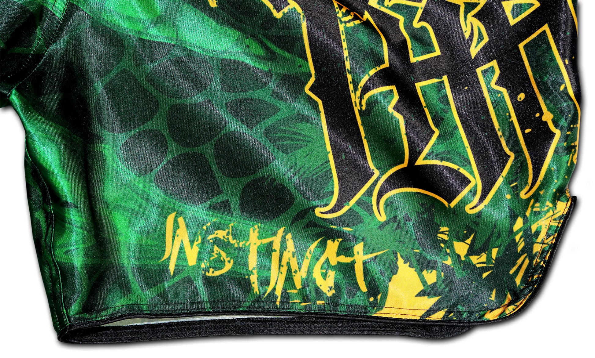 Detail of gold INSTINCT lettering and reptilian green satin on YAKSHA Rumble in the Jungle Fight Shorts