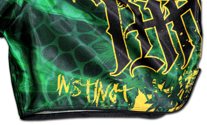 Detail of gold INSTINCT lettering and reptilian green satin on YAKSHA Rumble in the Jungle Fight Shorts