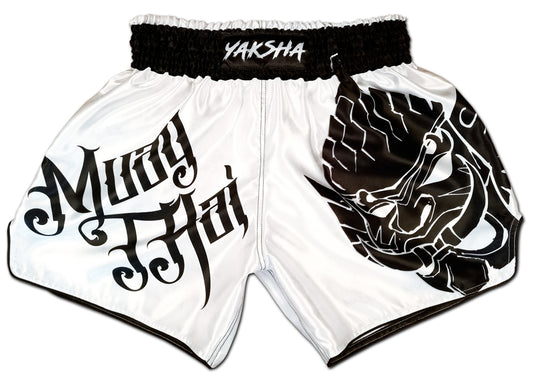 YAKSHA Yin and Yang fight shorts front view, white satin with bold Muay Thai calligraphy and black Yaksha demon panel