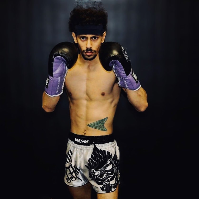 Fighter in guard stance wearing YAKSHA Yin and Yang white and black satin shorts with boxing gloves