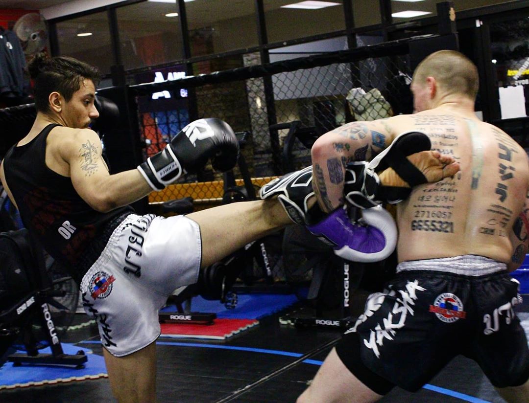 Fighter wearing YAKSHA Yin and Yang satin shorts during sparring session, white and black design in action