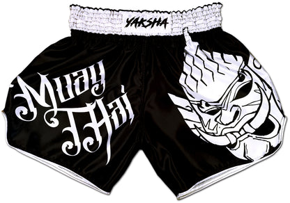 YAKSHA Yin Yang Thai fightshorts front view, black satin with white Muay Thai calligraphy and fierce white Yaksha demon panel
