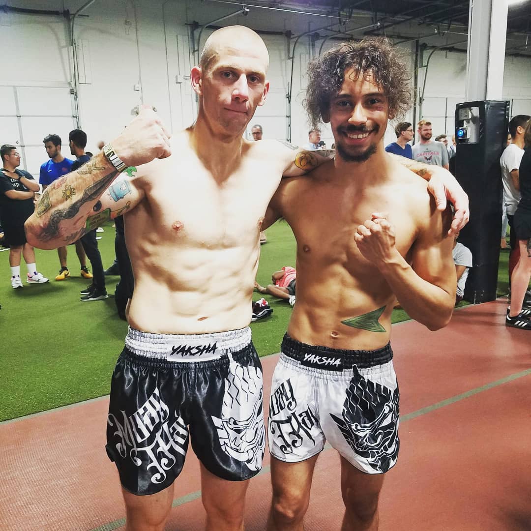 Two fighters wearing matching YAKSHA Yin Yang fightshorts, black and white versions side by side at the gym