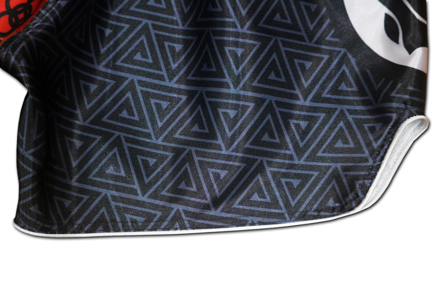 Detail of black geometric triangle pattern and white piping seam on BLACK PANTHER Adinkra fight shorts