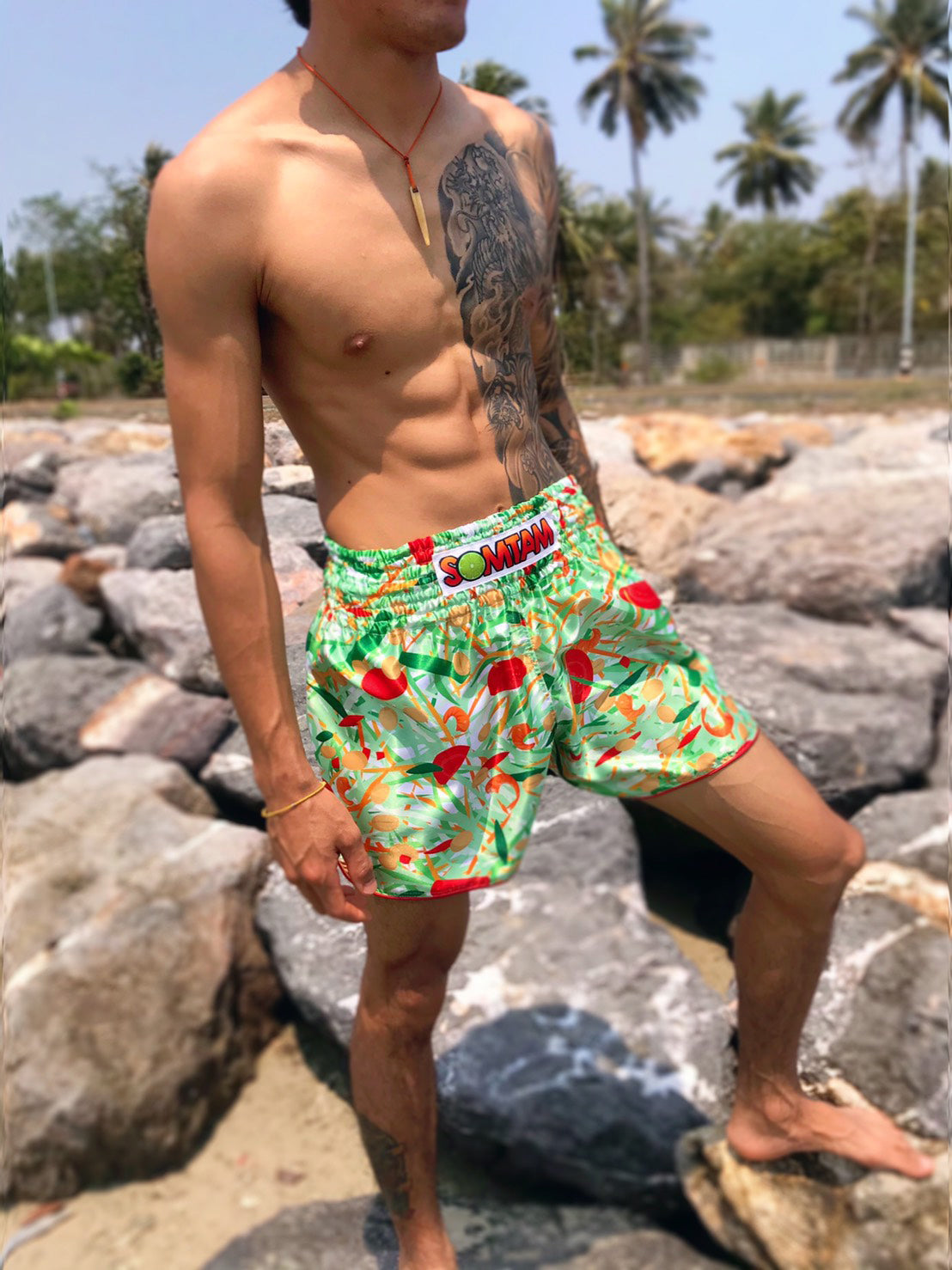 Close up of Thai fighter wearing SOM TAM Muay Thai Shorts on rocky beach in Thailand