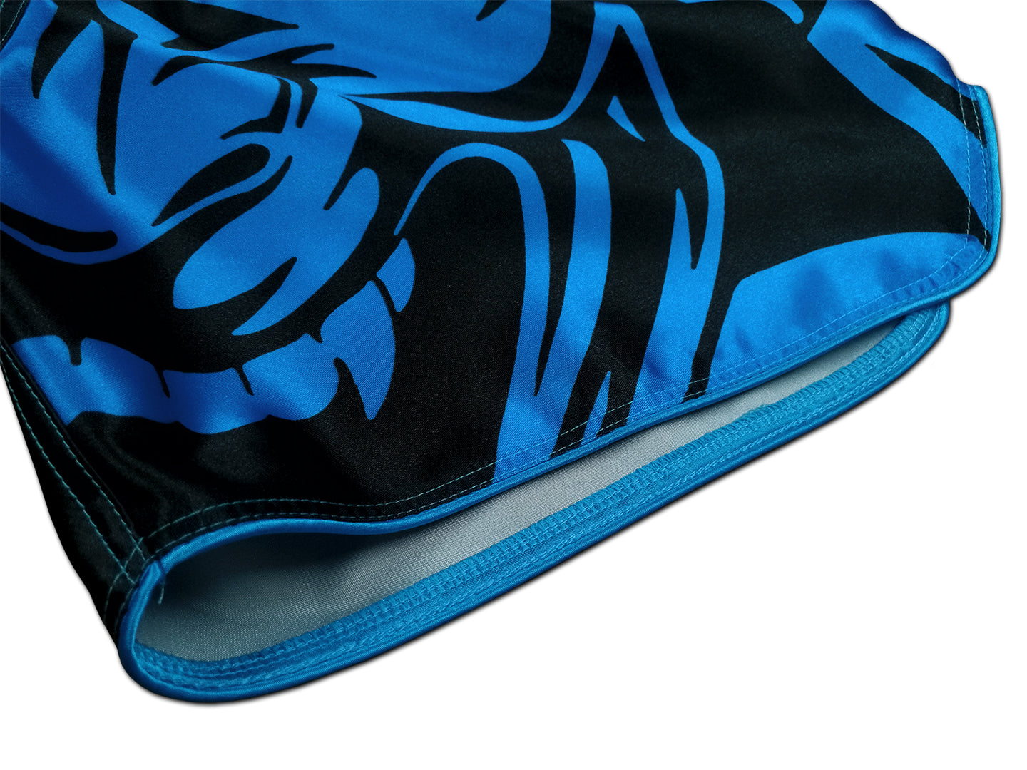 Detail of electric blue oni demon face with sharp fangs and tribal patterns printed on smooth black satin Thai fightwear