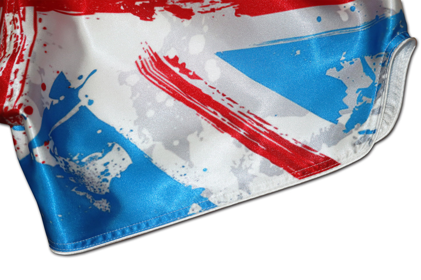 Detail of glossy satin fabric, red paint strokes and reinforced white side stitching on Union Jack Fight Shorts