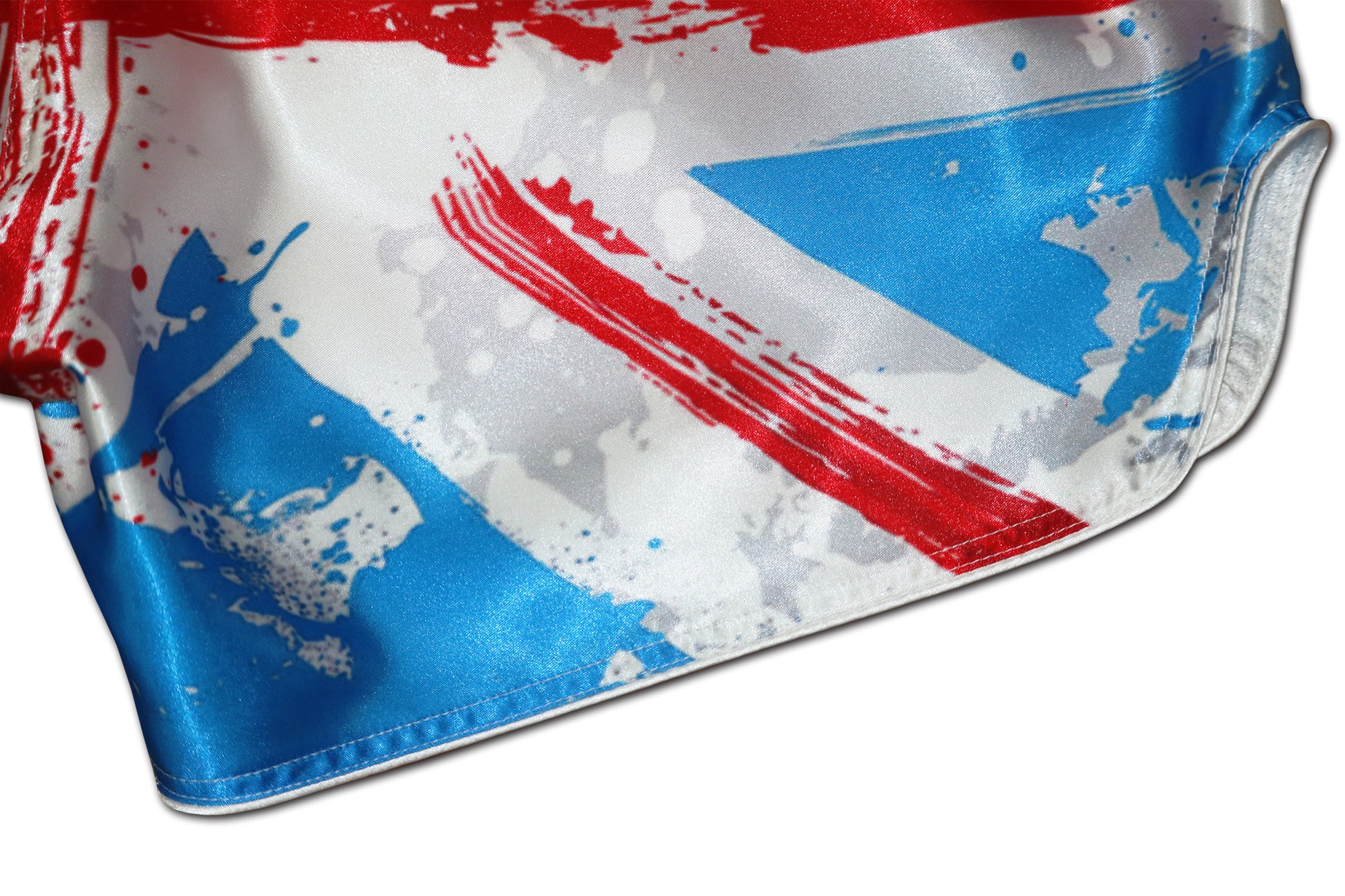 Detail of glossy satin fabric, red paint strokes and reinforced white side stitching on Union Jack Fight Shorts