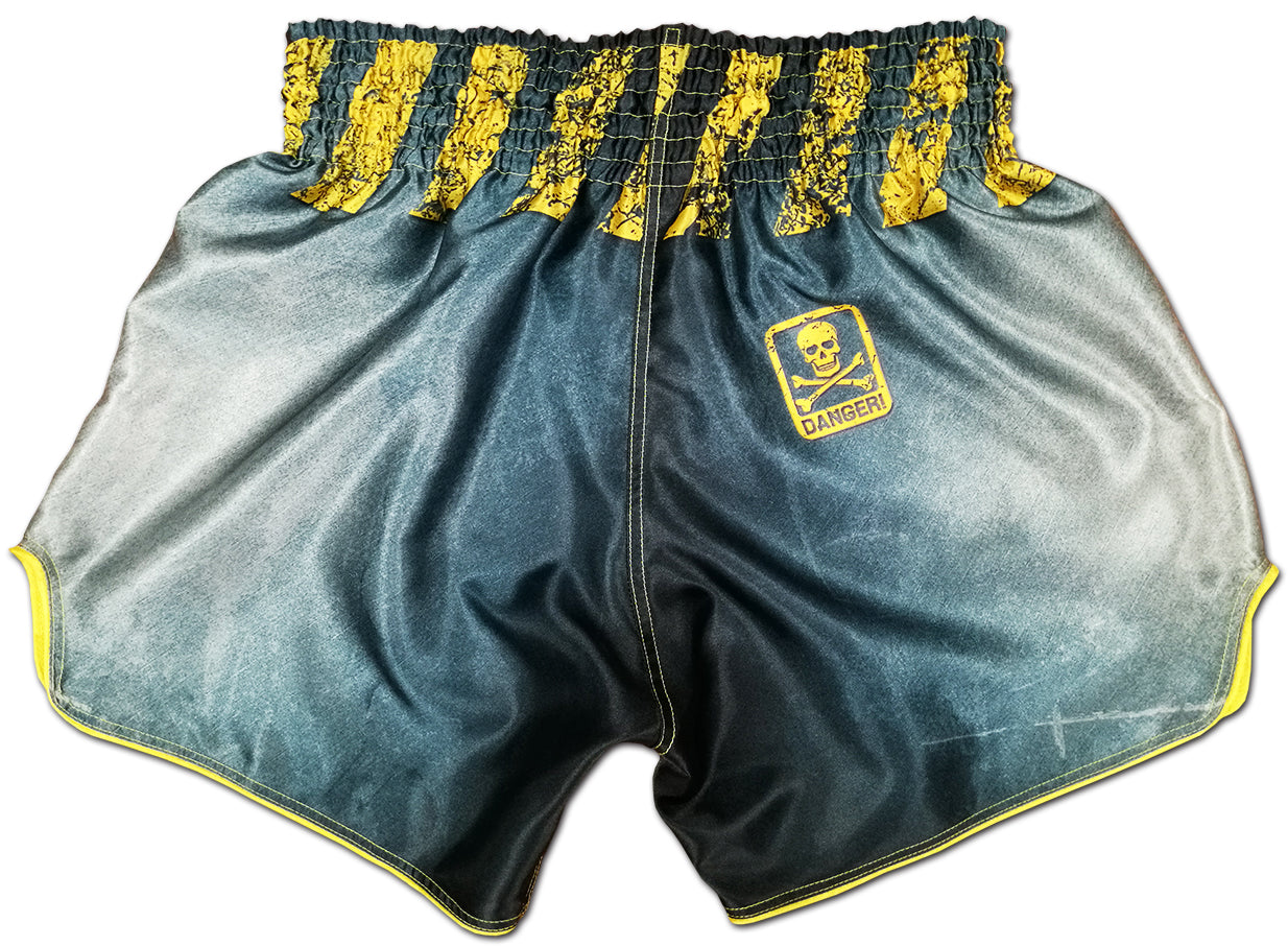 Back view of gray and yellow Thai boxing shorts with yellow skull and crossbones DANGER badge