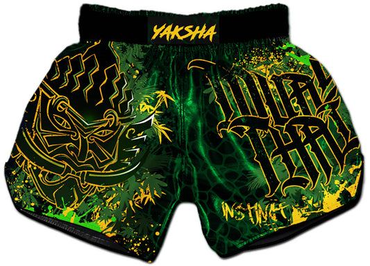 YAKSHA Rumble in the Jungle Fight Shorts front view, black and green satin with gold Yaksha demon and Muay Thai calligraphy